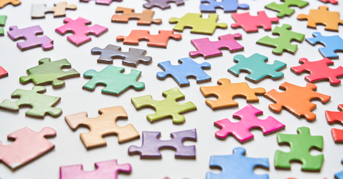 Vibrant jigsaw puzzle pieces scattered on a white background in a still life composition.